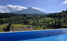 Infinity pool overlooking Mount Agung and Bali rice fields, symbolizing personal transformation and the courage to take chances.